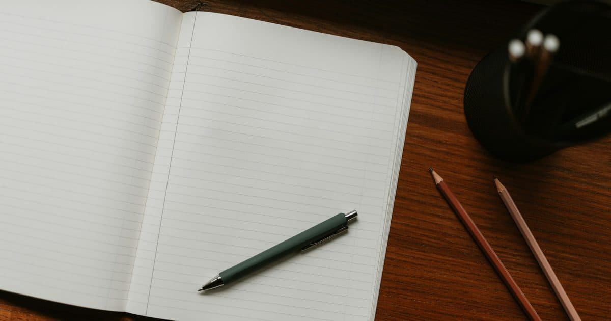 Notebook aperto con penna e matite su una scrivania in legno, foto reale che rappresenta il lavoro sobrio ed essenziale del sistema minimo