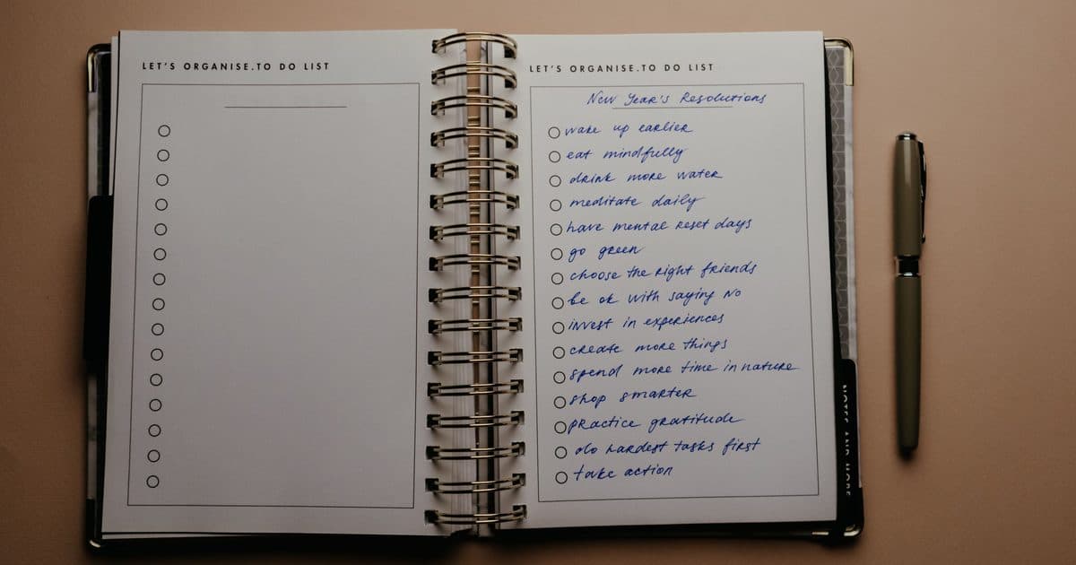 Agenda planner aperta con to-do list scritta a mano e una penna, vista dall'alto