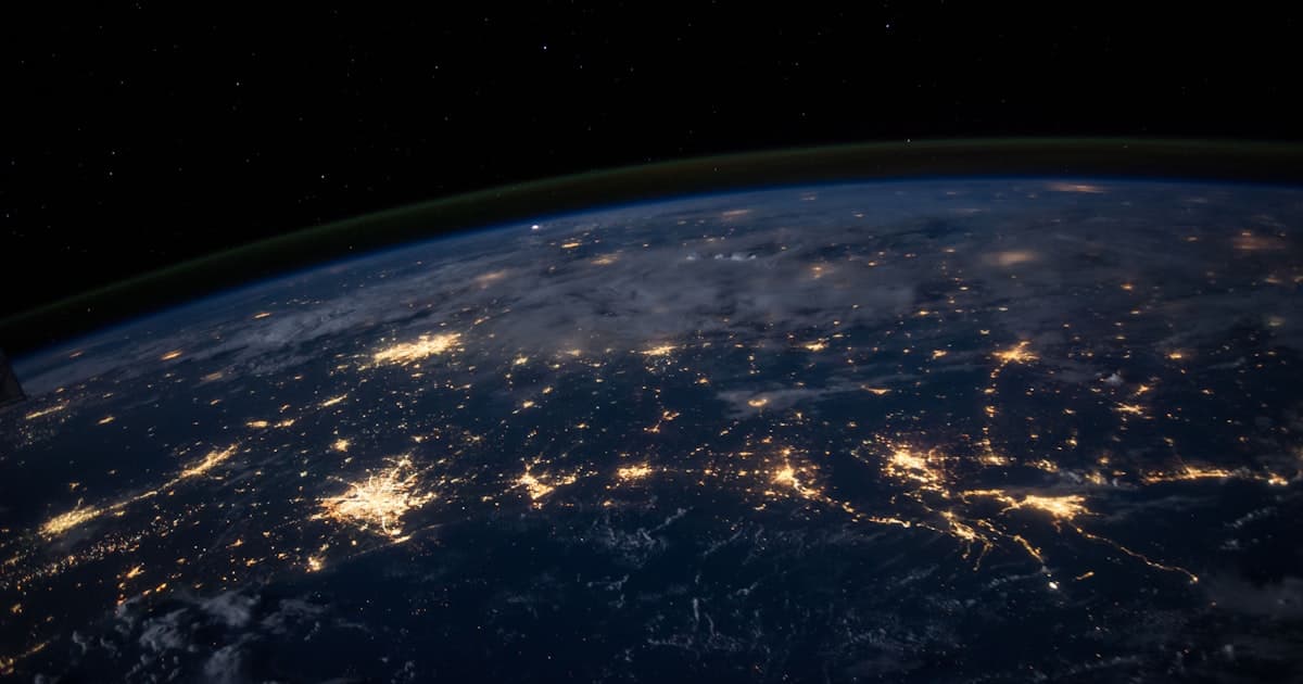 Vista notturna della Terra dallo spazio, con le luci delle città collegate da reti luminose: la prospettiva dall'alto necessaria prima di scegliere una nuova direzione professionale dopo i 40 anni
